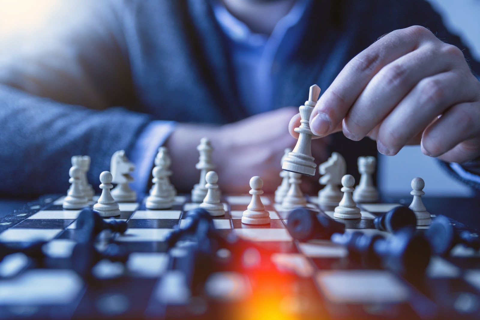 Person in casual clothing strategizing on a chessboard with finger pointing at chess piece.