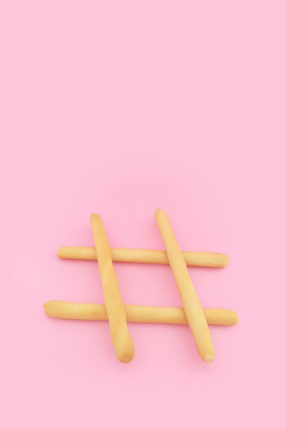 four brown wooden sticks on pink surface