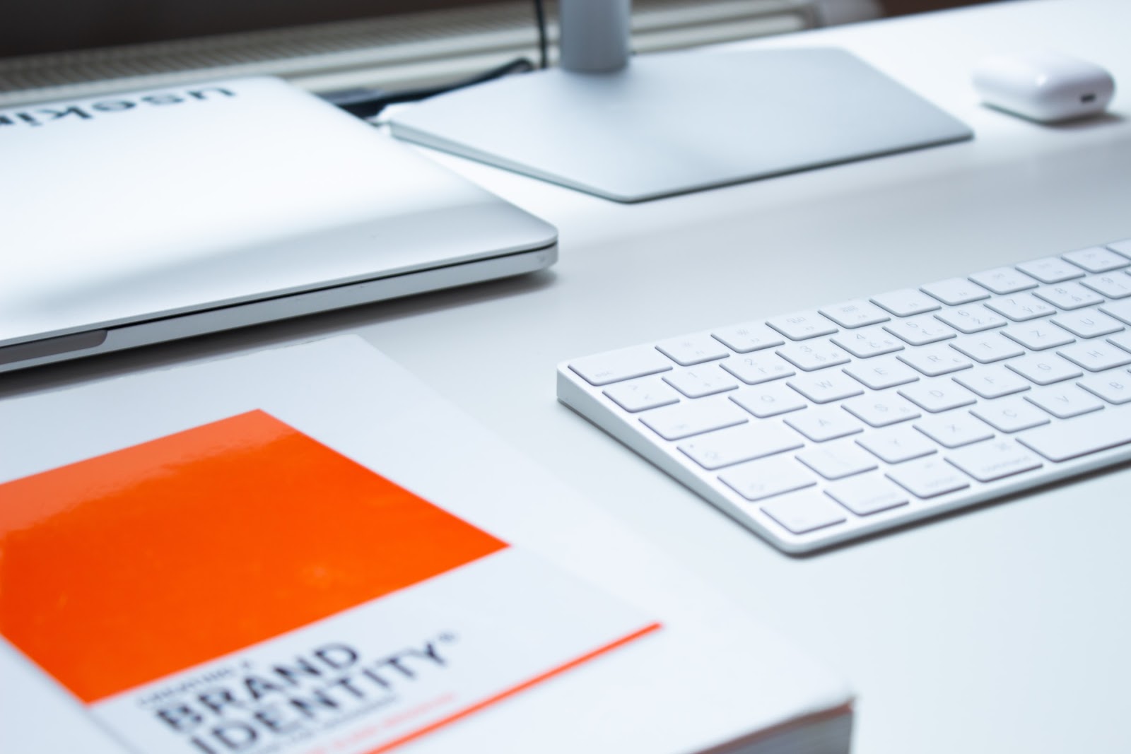 Table with computer peripherals, keyboard, and laptop on a desk, displaying text "BRAND IDENTITY".