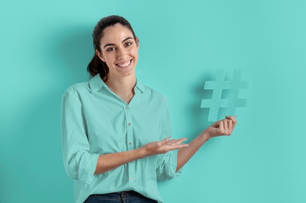 Smile woman holding the hashtag sign Free Photo