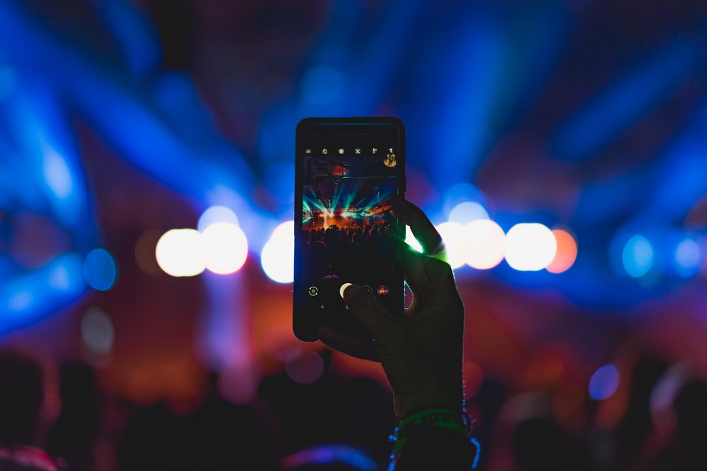 person taking photo of live concert
