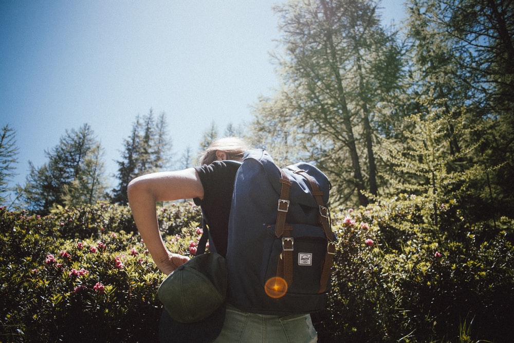 woman carrying bucket backpack facing backward